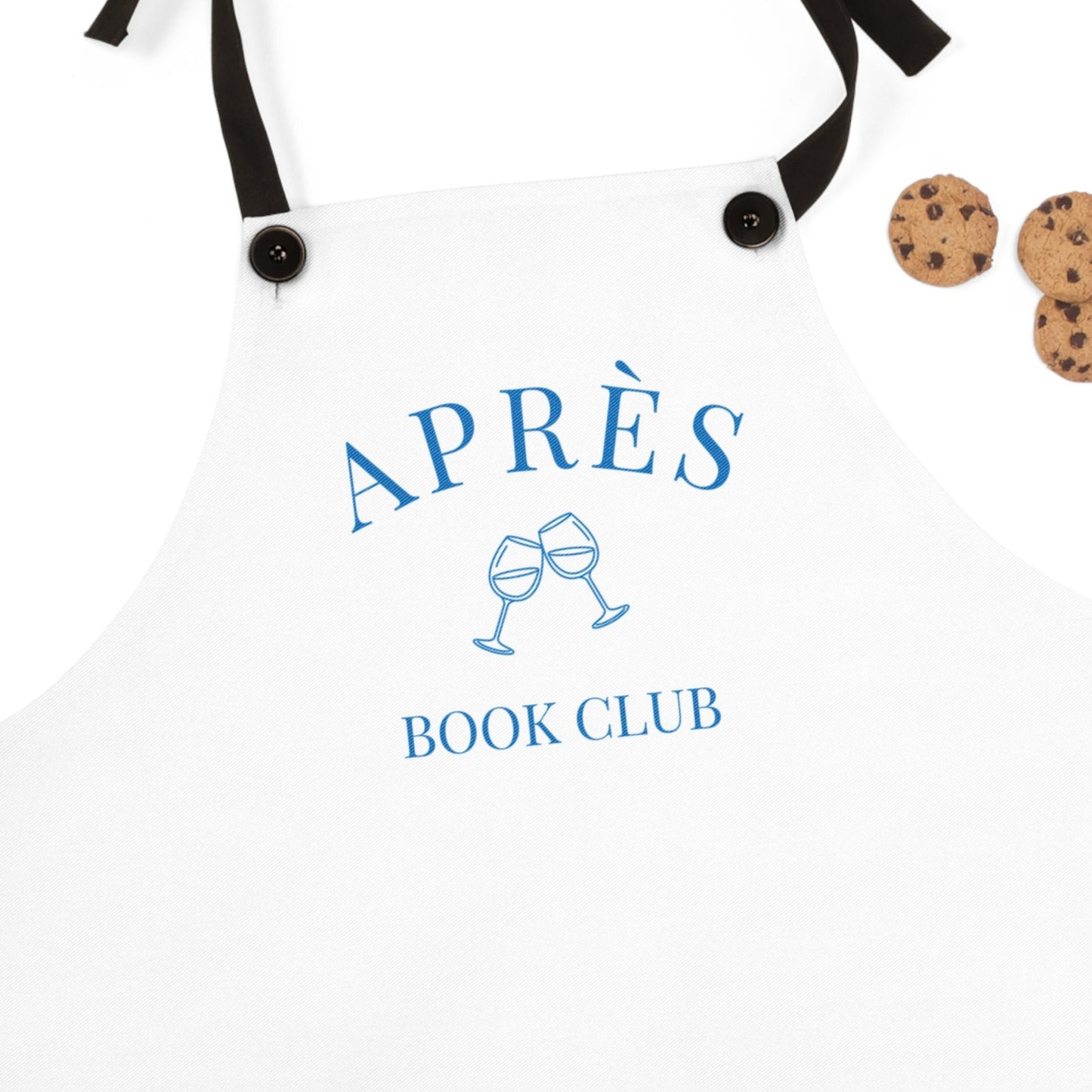 White apron with 'APRÈS BOOK CLUB' text and wine glass icons, accompanied by cookies on a white background.