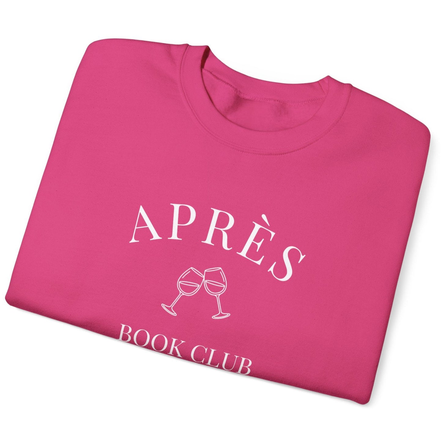 Folded pink sweatshirt with 'APRÈS BOOK CLUB' text and wine glass graphics on a white background