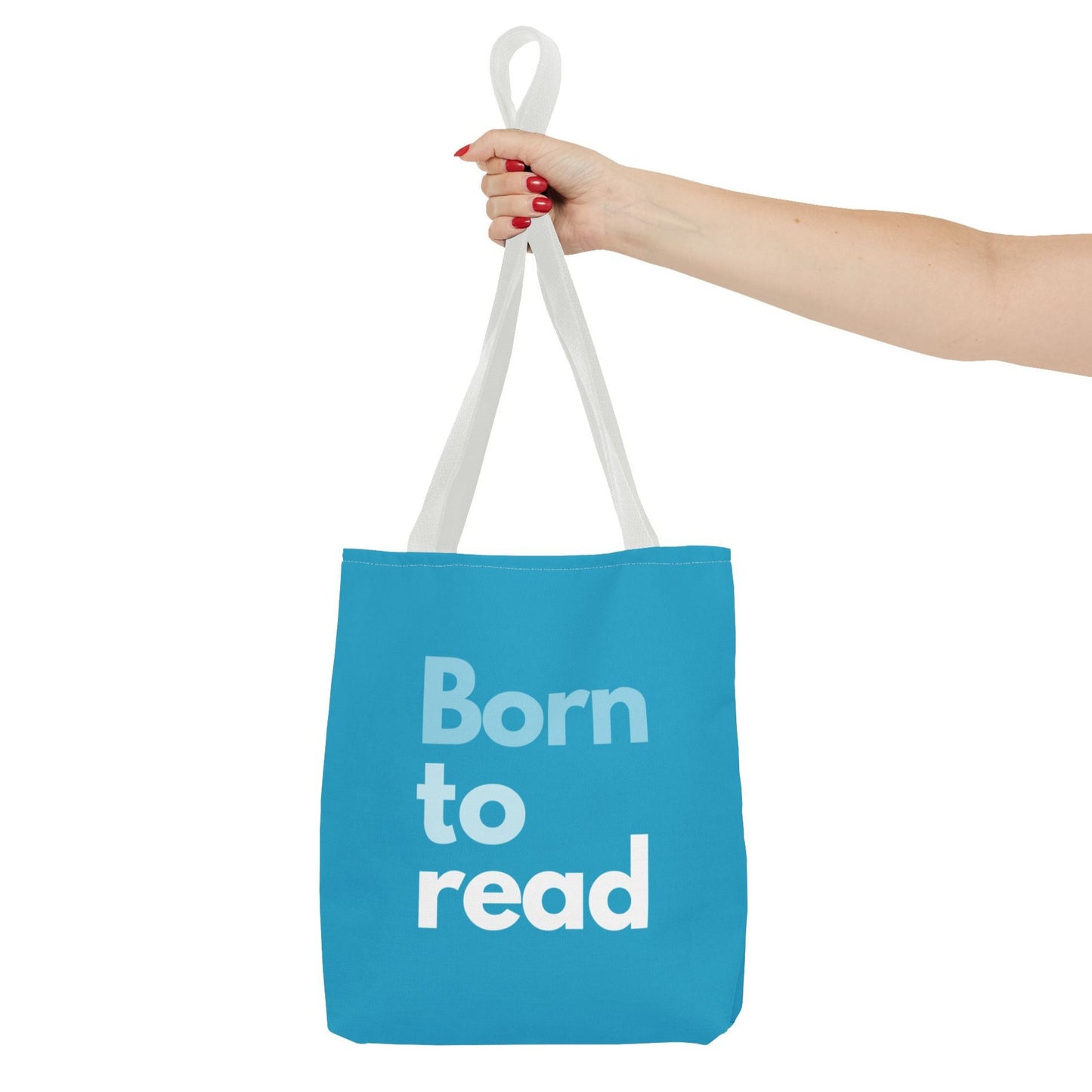 Blue tote bag with 'Born to read' text held by a hand on a white background