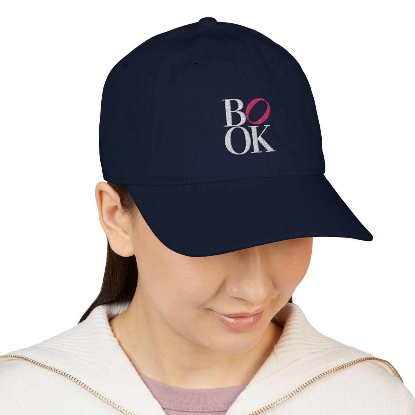 Person wearing a navy blue cap with 'BOOK' logo on a white background