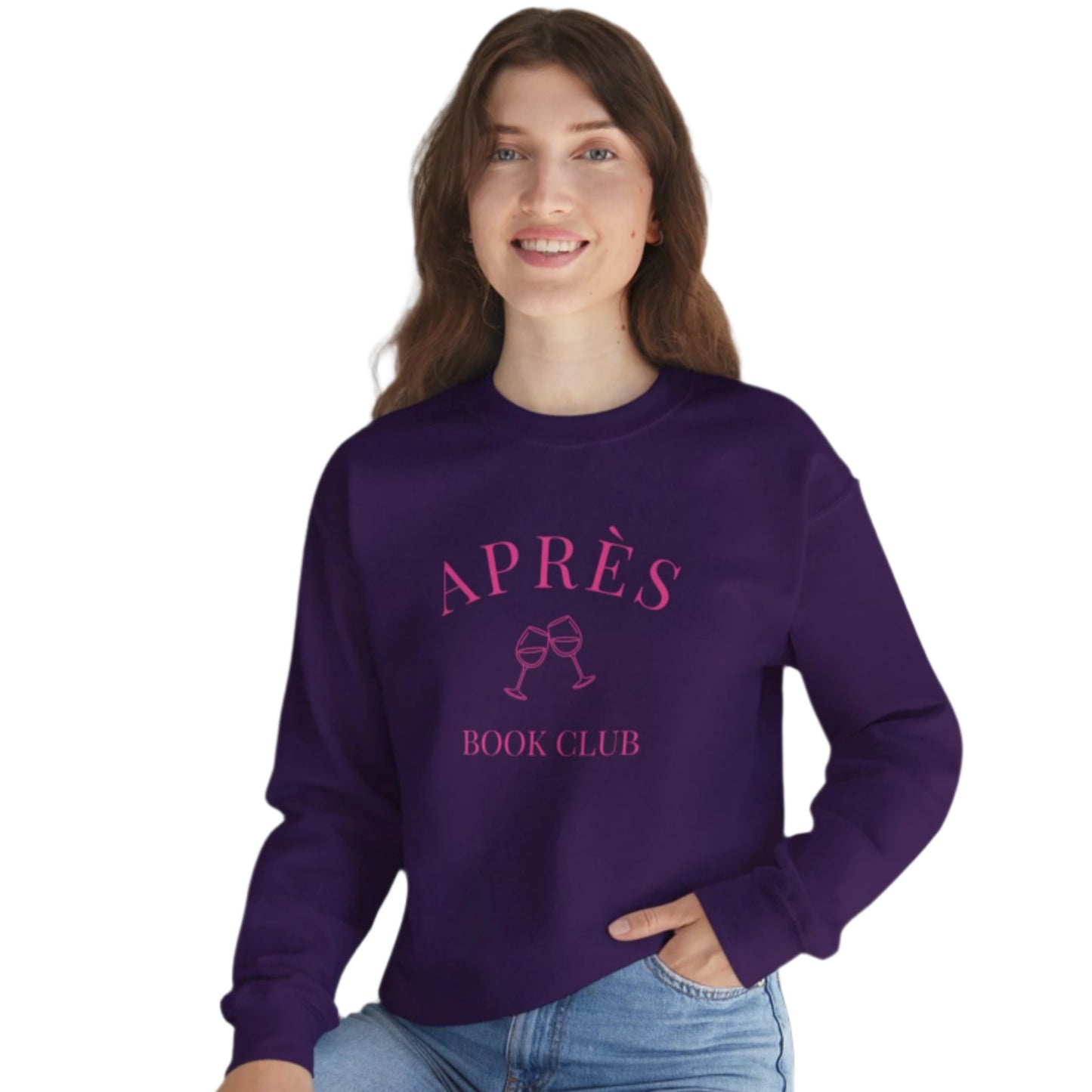 Woman wearing a purple sweatshirt with 'APRÈS BOOK CLUB' text, sitting on a white surface with a plant in the background.