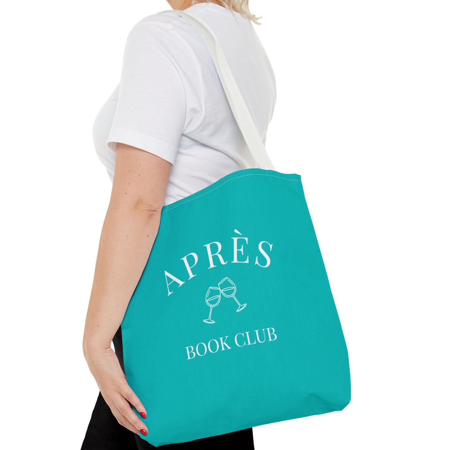 Person holding a teal tote bag with 'APRÈS BOOK CLUB' text and graphics.