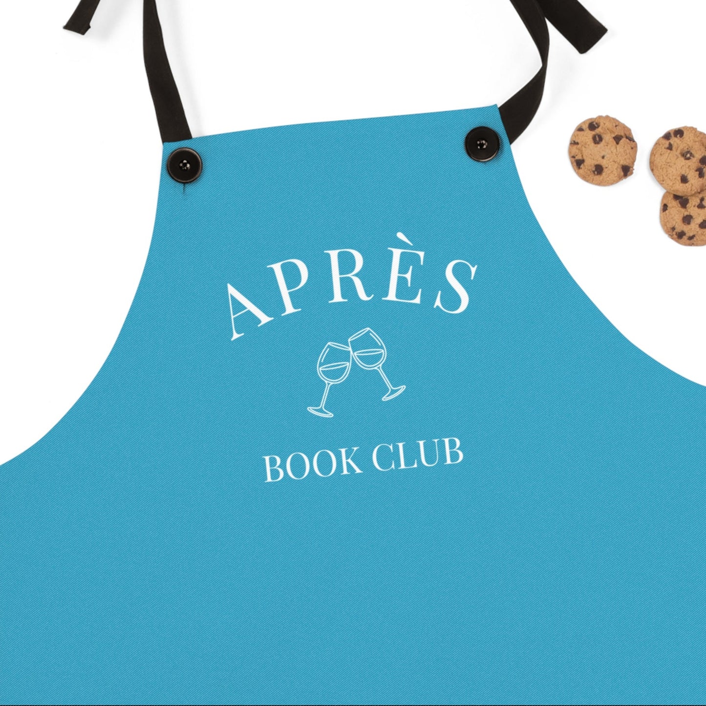 Blue apron with 'APRÈS BOOK CLUB' text and wine glass design, accompanied by cookies on a white background.