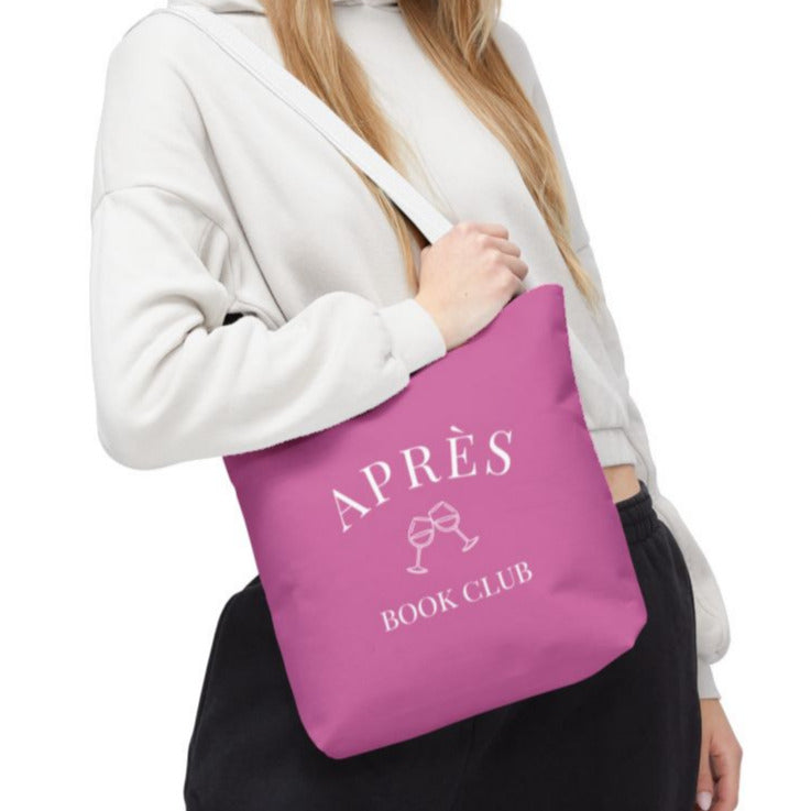 Person holding a pink tote bag with 'APRÈS BOOK CLUB' text