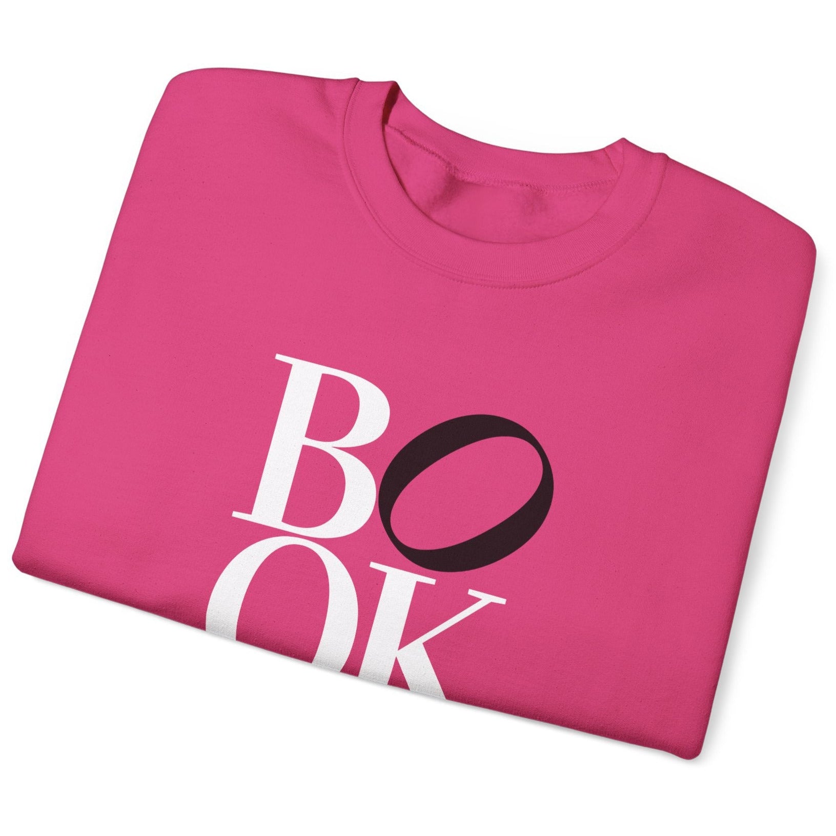 Folded pink sweatshirt with 'BOOK' printed on it against a white background