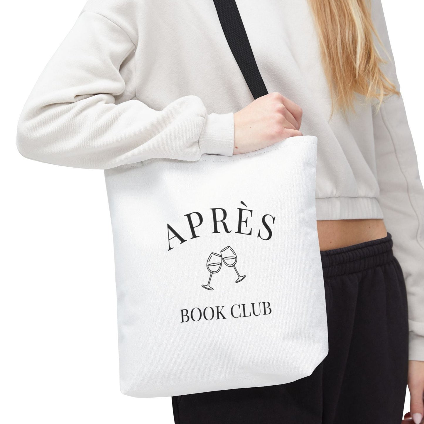 Person holding a white tote bag with 'Ap
es Book Club' text and graphics.