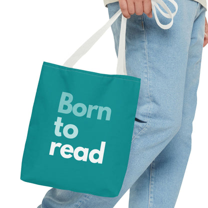 Teal tote bag with 'Born to read' text held by a person wearing jeans.