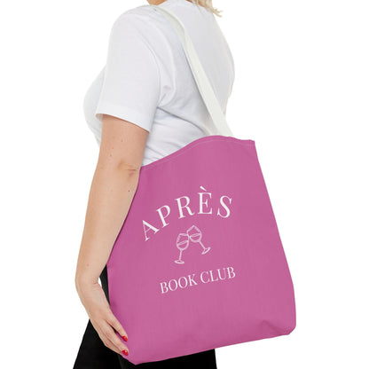 Person holding a pink tote bag with 'Apes Book Club' text and wine glass graphics.