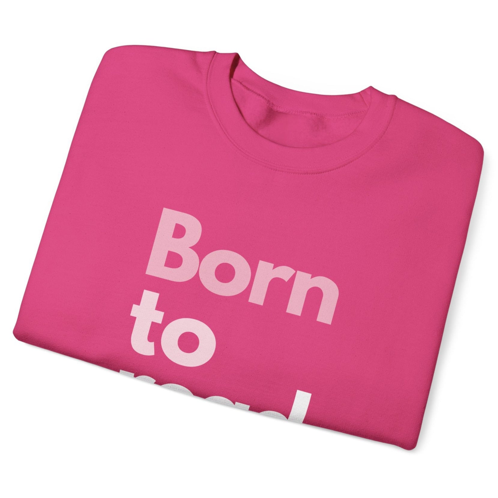 Folded pink t-shirt with 'Born to' text on a white background